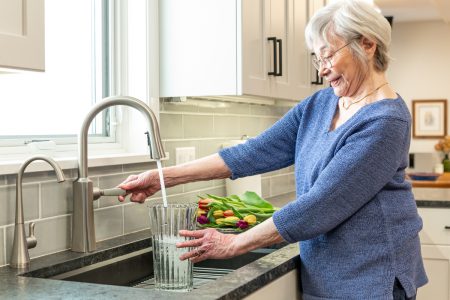 Woman filling vase with water in her kitchen sink