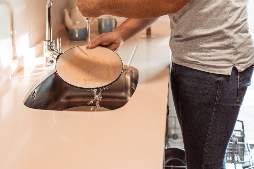 Homeowner rinsing a plate in the kitchen sink