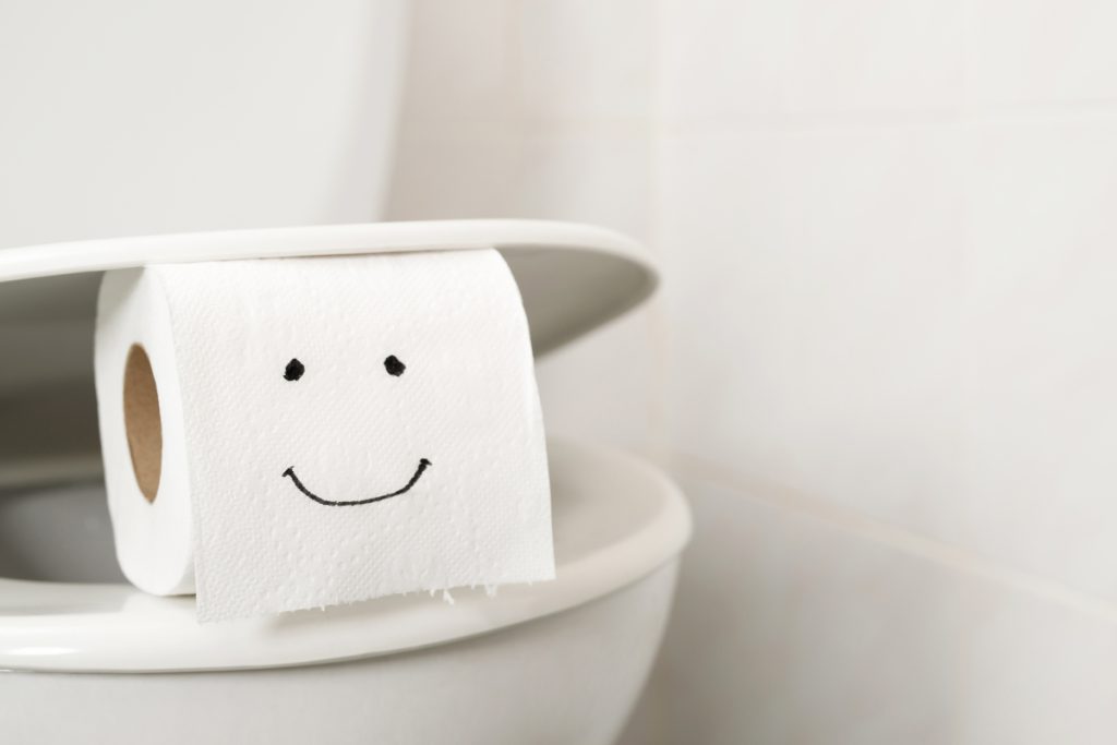 Toilet paper roll with a smiley face drawn on it.