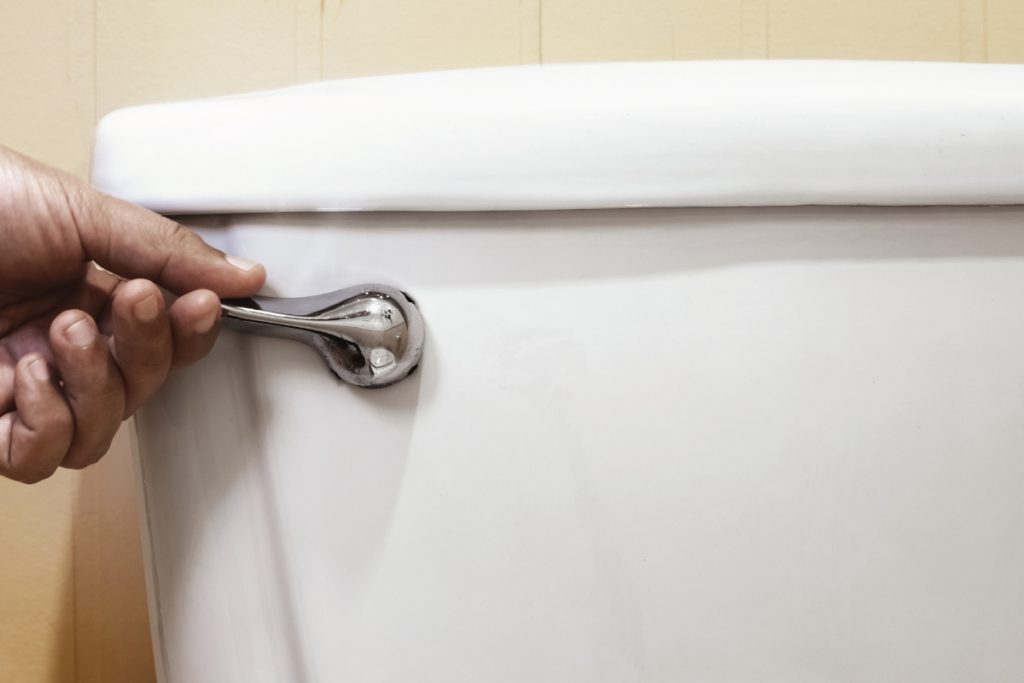 Closeup of hand flushing a toilet