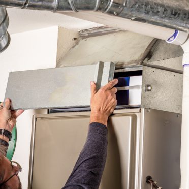 Man removes the furnace filter cover to inspect filter